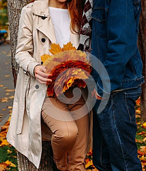 Love, relationship, family and people concept - close up of couple with maple leaf kissing in autumn park