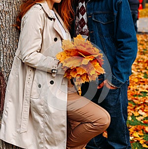 Love, relationship, family and people concept - close up of couple with maple leaf kissing in autumn park