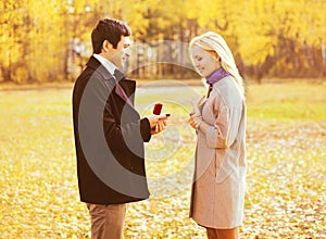 Love, relationships, engagement and wedding concept - man proposes a woman to marry, red box ring, happy young romantic couple