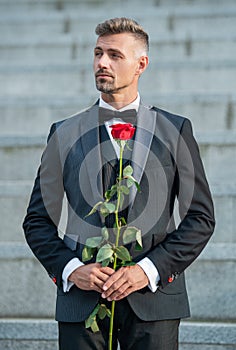 love rendezvous concept. adult tuxedo man with love rose. flower gift for love day