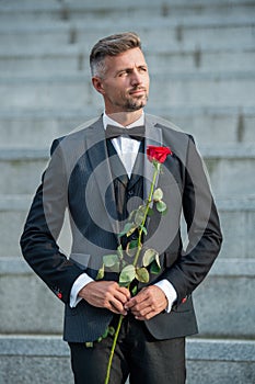 love rendezvous concept. caucasian tuxedo man with love rose. flower gift for love day