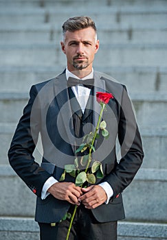 love rendezvous concept. elegant tuxedo man with love rose. flower gift for love day
