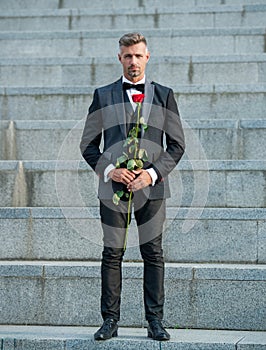 love rendezvous concept. rich tuxedo man with love rose. flower gift for love day