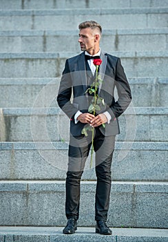 love rendezvous concept. tuxedo man with love rose. flower gift for love day. full length