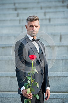 love rendezvous concept. tuxedo man with love rose. flower gift for love day. selective focus
