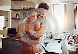 Love, romance and fun couple hugging, cooking in a kitchen and sharing an intimate moment. Romantic boyfriend and