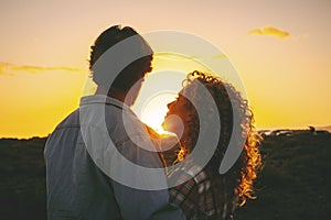 Love and romance outdoor leisure activity with man and woman hugging during golden sunset in outdoors leisure activity together.