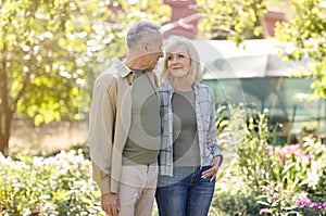 Love and romance in senior age concept. Loving senior spouses embracing and smiling to each other in their garden