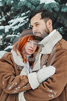 Love romantic couple lovestory. Brutal bearded man, bright red-haired girl woman in winter park. Romantic date, kissing photo