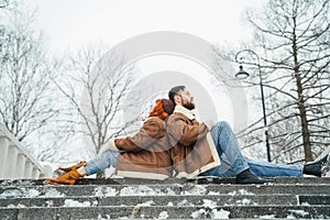 Love romantic couple lovestory. Brutal bearded man, bright red-haired girl woman in winter park. Romantic date, kissing