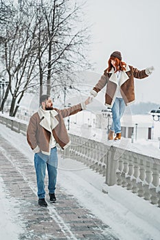 Love romantic couple lovestory. Brutal bearded man, bright red-haired girl woman in winter park. Romantic date, kissing