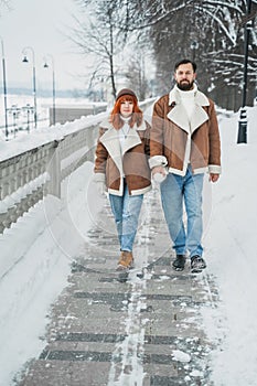 Love romantic couple lovestory. Brutal bearded man, bright red-haired girl woman in winter park. Romantic date, kissing