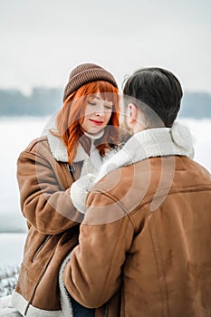 Love romantic couple lovestory. Brutal bearded man, bright red-haired girl woman in winter park. Romantic date, kissing