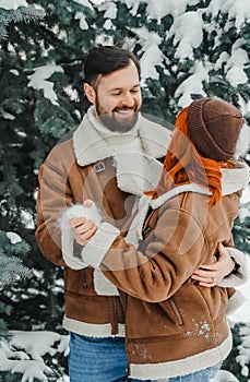 Love romantic couple lovestory. Brutal bearded man, bright red-haired girl woman in winter park. Romantic date, kissing