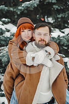 Love romantic couple lovestory. Brutal bearded man, bright red-haired girl woman in winter park. Romantic date, kissing