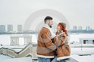 Love romantic couple lovestory. Brutal bearded man, bright red-haired girl woman in winter park. Romantic date, kissing