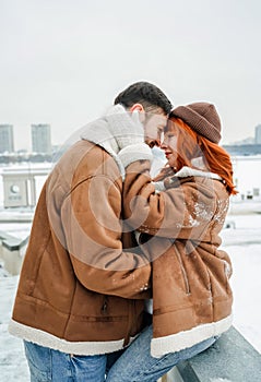 Love romantic couple lovestory. Brutal bearded man, bright red-haired girl woman in winter park. Romantic date, kissing