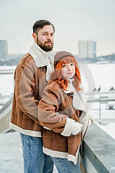 Love romantic couple lovestory. Brutal bearded man, bright red-haired girl woman in winter park. Romantic date, kissing