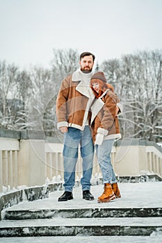 Love romantic couple lovestory. Brutal bearded man, bright red-haired girl woman in winter park. Romantic date, kissing