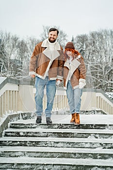 Love romantic couple lovestory. Brutal bearded man, bright red-haired girl woman in winter park. Romantic date, kissing