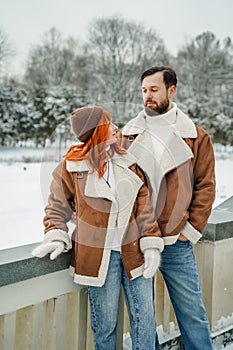 Love romantic couple lovestory. Brutal bearded man, bright red-haired girl woman in winter park. Romantic date, kissing