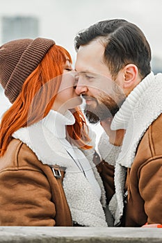 Love romantic couple lovestory. Brutal bearded man, bright red-haired girl woman in winter park. Romantic date, kissing