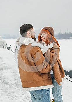 Love romantic couple lovestory. Brutal bearded man, bright red-haired girl woman in winter park. Romantic date, kissing