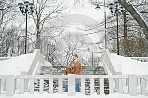 Love romantic couple lovestory. Brutal bearded man, bright red-haired girl woman in winter park. Romantic date, kissing