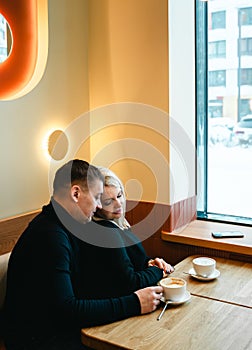Love romantic couple lovestory. Man hugging woman, kissing blonde girl in cozy coffee shop cafe. Romantic family date