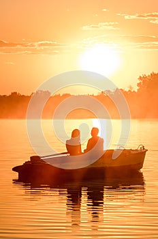 Love and romantic golden river sunset. Silhouette of couple on boat backlit by sunlight