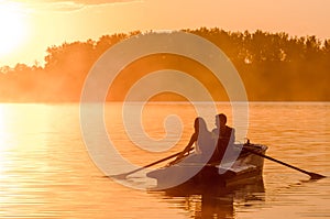 Love and romantic golden river sunset. Silhouette of couple on boat backlit by sunlight