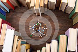 Love science concept. Books stacked in heart shape and molecule model on wooden desk. Take a degree in natural Sciences