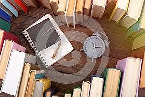 Love science concept. Heart shape of books, graduate cap and clock on wooden desk. Time to take a degree in natural Sciences