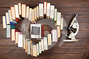 Love science concept. Heart shape of books, microscope and molecule model on wooden desk. Take a degree in natural Sciences