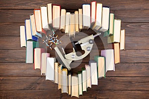 Love science concept. Heart shape of books, microscope and molecule model on wooden desk. Take a degree in natural Sciences