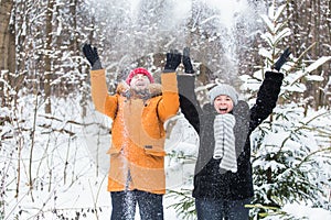 Love, season, friendship and people concept - happy young man and woman having fun and playing with snow in winter forest