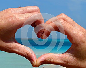 Love shape hand silhouette over Pelosa beach at Sardinia, Italy