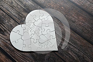 Love shape white puzzle on top of wooden table. Love and caring conceptual