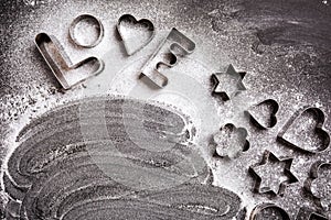 Love shaped cookie cutters and flour on black