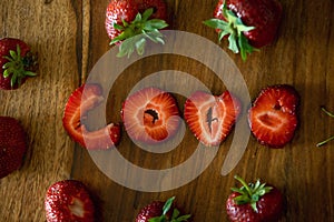 Love sign made from strawberry pieces on a table, whote strawberries around