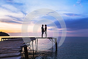 Love, silhouette of affectionate couple on the pier at sunset beach