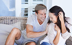 Love, smile and couple tickle on sofa at home, bonding and fun together. Happy man, woman and play in living room for