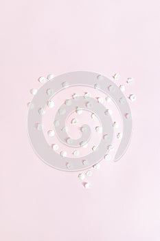 Love spring concept. White apricot petals laid out in the shape of heart on pink background. Flat lay. Vertical frame
