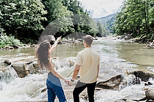 Love story of couple. Travelling in Karpathian mountains. Waterfall in mountain river. Cascade waterfall and happy