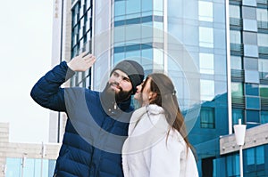 Love story of couple walking in city. Young business man in a blue jacket with a beard. And a cute woman in long coat