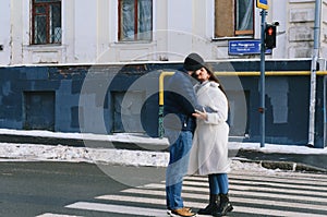 Love story of couple walking in city. Young business man in a blue jacket with a beard. And a cute woman in long coat