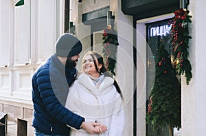 Love story of couple walking in city. Young business man in a blue jacket with a beard. And a cute woman in long coat