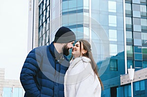 Love story of couple walking in city. Young business man in a blue jacket with a beard. And a cute woman in long coat