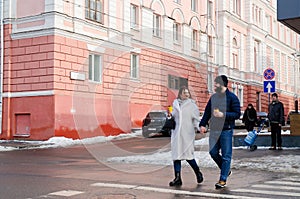 Love story of couple walking in city. Young business man in a blue jacket with a beard. And a cute woman in long coat