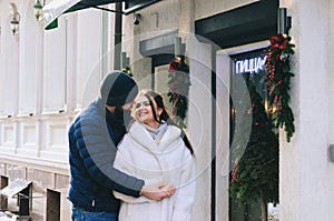 Love story of couple walking in city. Young business man in a blue jacket with a beard. And a cute woman in long coat